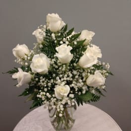 White roses arranged in a clear glass vase with baby's breath