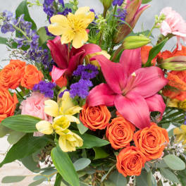 Bright mixed bouquet with orange roses, pink lilies, and purple flowers
