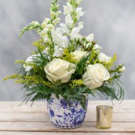 White roses and snapdragons in a blue-and-white ceramic vase