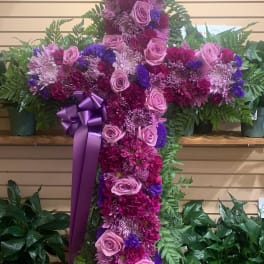 Large floral cross with pink and purple flowers and a ribbon bow