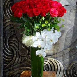 Red roses and white orchids in a tall green vase