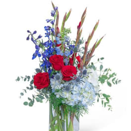 Red roses and blue flowers in a clear glass vase