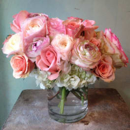 Pink and peach roses with white blooms in a clear glass vase