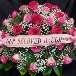 Pink rose funeral spray with a ribbon reading "Our Beloved Daughter"