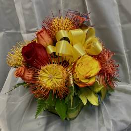 Bouquet of red, yellow, and orange roses with spiky blooms and a yellow ribbon