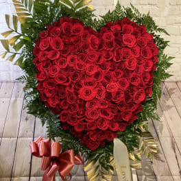 Heart-shaped red rose arrangement with ribbon and greenery