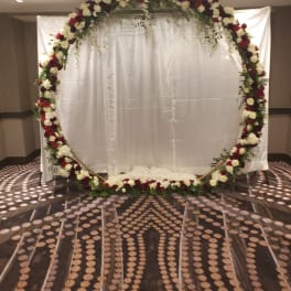 Large floral arch with red and white roses in front of a white backdrop