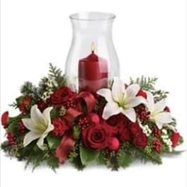 Red floral centerpiece with a candle in a glass hurricane vase