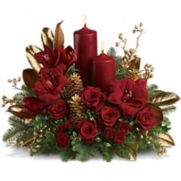 Red roses with two red candles and gold accents in a holiday arrangement
