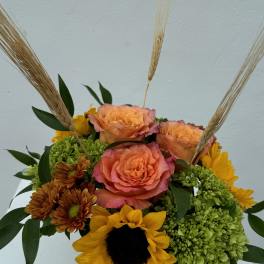 Bouquet of peach roses, sunflowers, and green hydrangeas with wheat stems