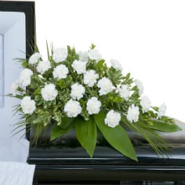 White floral casket spray with green foliage