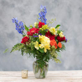 Colorful mixed bouquet in a glass vase with tall blue flowers