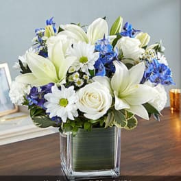 Blue and white flower arrangement in a clear square vase
