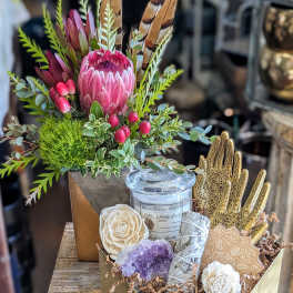 Gift box with a protea arrangement, candle, crystals, and decorative hands