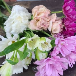 Assorted pink, white, and purple flowers laid on a dark surface