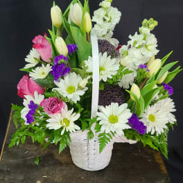 Basket arrangement of white daisies, pink roses, and tulips