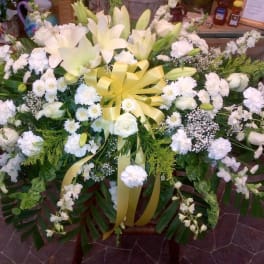 Large white floral spray with lilies, roses, and a yellow ribbon