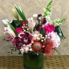Mixed bouquet with lilies, orchids, roses, and snapdragons in a green vase