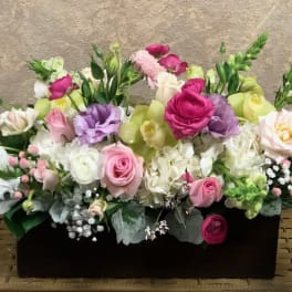 Mixed pink, white, and purple flowers in a black rectangular container