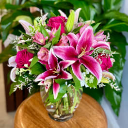Pink lilies and roses arranged in a clear glass vase