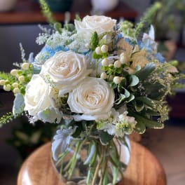 White rose bouquet in a glass vase with blue accents