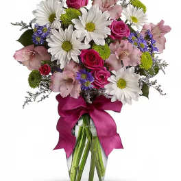 Bouquet of daisies, roses, and alstroemeria in a glass vase with a magenta ribbon