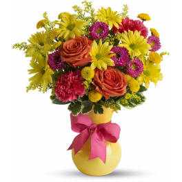 Bright bouquet of yellow daisies, orange roses and pink flowers in a yellow vase with a pink bow