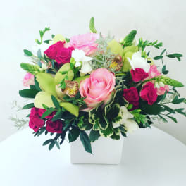 Mixed bouquet of pink and white flowers in a white square vase
