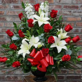 Red roses and white lilies in a black vase with a red bow