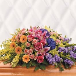 Colorful casket spray with lilies, roses, gerbera daisies, and hydrangeas