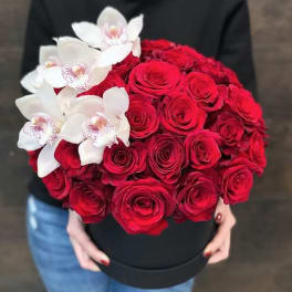 Red roses with white orchids in a black hat box