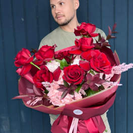 Man holding a large bouquet of red roses and pink flowers