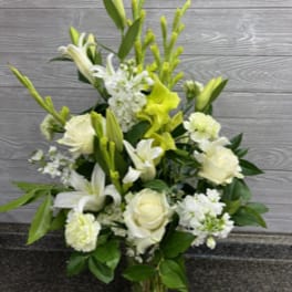 White and pale yellow floral arrangement in a clear glass vase