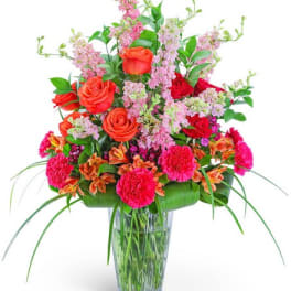 Mixed bouquet of roses, carnations, and pink filler flowers in a glass vase