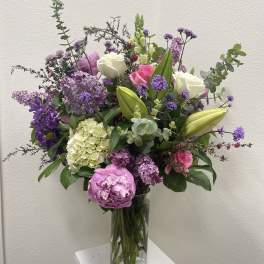 Mixed bouquet of pink, purple, and white flowers in a clear glass vase
