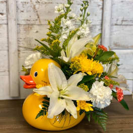 Yellow duck-shaped container filled with white and yellow flowers
