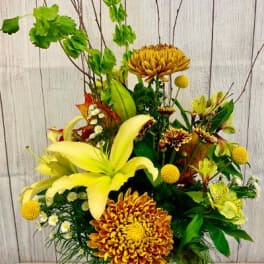Yellow lilies and chrysanthemums in a glass vase with tall branches