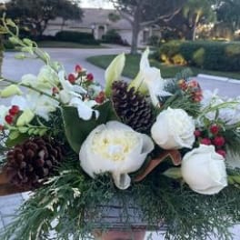 White floral arrangement with pinecones and red berries in a container