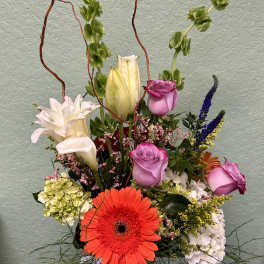 Mixed bouquet with roses, lilies, and a bright gerbera daisy in a glass vase