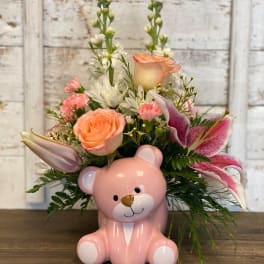 Pink teddy bear vase holding a mixed bouquet of roses and lilies