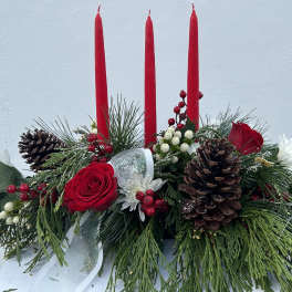 Holiday centerpiece with red candles, roses, pinecones, and evergreen branches