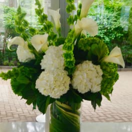 White calla lilies and hydrangeas in a glass vase
