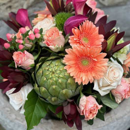 Bouquet with peach roses, coral gerbera daisies, and a green artichoke centerpiece