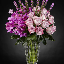 Pink roses and purple orchids in a clear glass vase