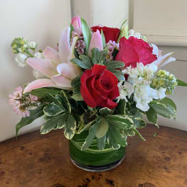 Bouquet of red roses and pink lilies in a green glass vase
