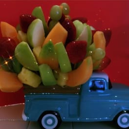 Fruit arrangement in a blue toy truck with strawberries and melon pieces