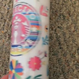 A decorated white tumbler with colorful floral and rainbow graphics.