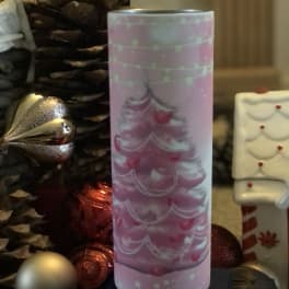 Pink Christmas tree candle holder beside pinecones and ornaments
