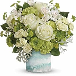 White roses and green flowers arranged in a blue glass vase