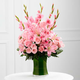 Pink floral arrangement in a green glass vase